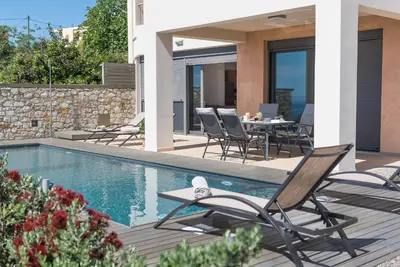 a villa with a swimming pool with chairs and a table at Luxury Villa Mystique with Amazing Seaview in Chania Town