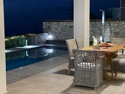 a patio with a table and chairs next to a pool at Luxury Villa Mystique with Amazing Seaview in Chania Town