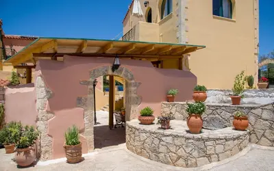 a house with a stone wall and potted plants at Skandalis Apartments with pool in Chorafakia