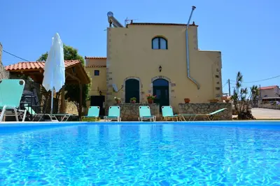 a villa with a swimming pool in front of a house at Skandalis Apartments with pool in Chorafakia