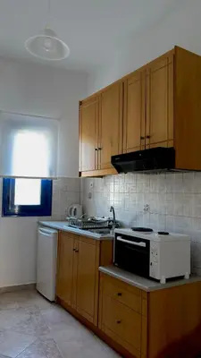 a kitchen with wooden cabinets and a stove top oven at Mesohori studios in Sfakiá