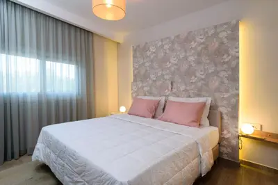 a bedroom with a large white bed with pink pillows at Iliana Apartments in Falasarna