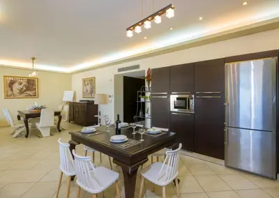 a kitchen with a table with white chairs and a refrigerator at Manolia Dream Apartment 3-bedrooms 30m to the beach in Agia Marina Nea Kydonias