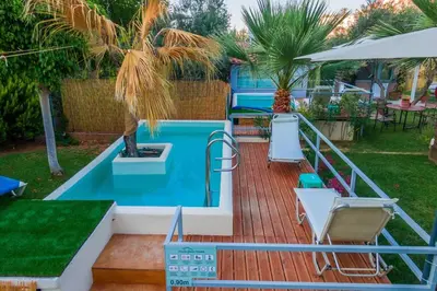 a deck with a pool and a table and chairs at Chania Green House 2 in Aghii Apostoli