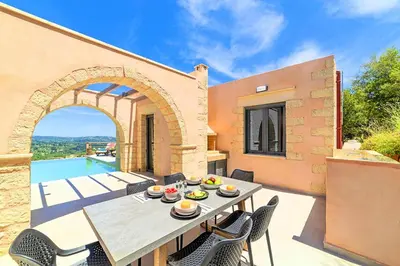 a patio with a table and chairs and a pool at Villa Vardis Heated Pool in Vryses