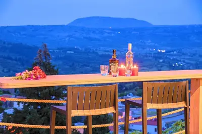 a table with two bottles and two chairs and candles at Villa Vardis Heated Pool in Vryses