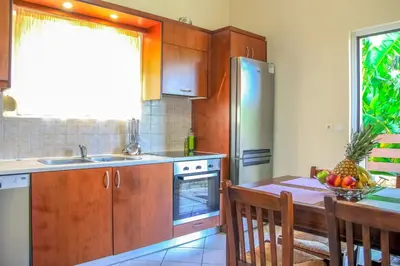a kitchen with wooden cabinets and a table with a bowl of fruit at Villa Panagiotis Chania in Daratso