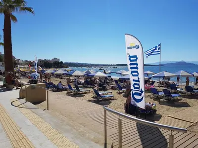 a beach with umbrellas and chairs and a large sail at Palm Luxury Studios in Chania Town