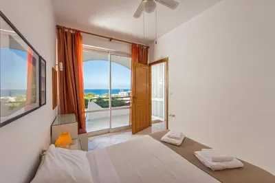 a bedroom with a bed and a view of the ocean at Rouladina Apartments in Stalos