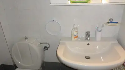 a white bathroom with a toilet and a sink at Summer Holidays Studio in Chania Town