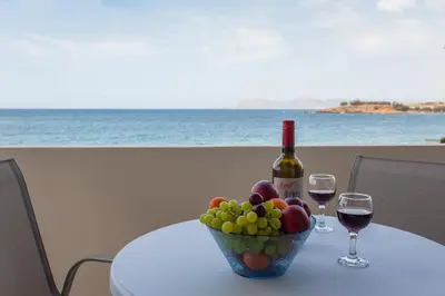 a table with a bowl of fruit and a bottle of wine at Lily of Crete 2 - Sea & Beach front Apartment in Kato Galatas