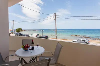 a table with a glass of wine and a view of the ocean at Lily of Crete 2 - Sea & Beach front Apartment in Kato Galatas