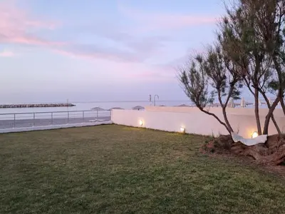 a yard with a wall and a tree and the beach at Amoutsa Seaside Villa in Kolymvari