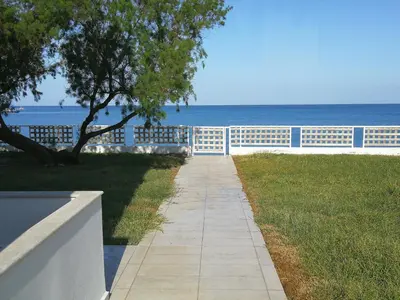 a walkway next to the ocean with a white fence at Amoutsa Seaside Villa in Kolymvari