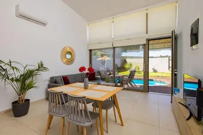 a dining room and living room with a table and chairs at Cocoon Luxury Villas in Maleme