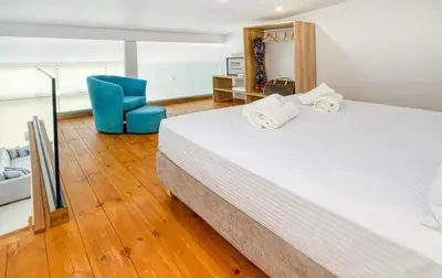 a bedroom with a large bed and a blue chair at Cocoon Luxury Villas in Maleme