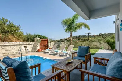 a patio with a table and chairs and a pool at Villa Vasiliki in Stalos