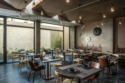 a restaurant with tables and chairs and large windows at Chania Flair Boutique Hotel, Adults only, Tapestry Collection by Hilton in Chania Town