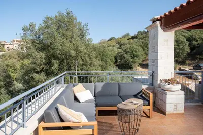 a patio with a couch and tables on a balcony at Prinus Country Retreat Apokoronas, heated pool, 13km from the sea in Embrósneros