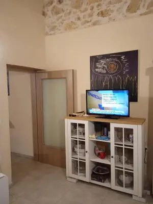 a living room with a television on a white cabinet at Spartis House 30m from the beach in Chania Town