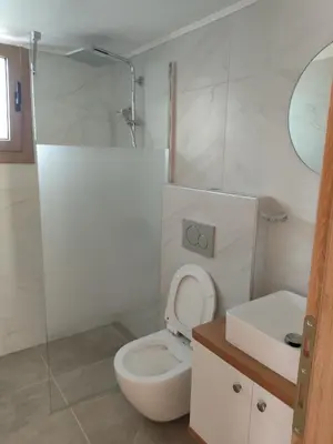 a white bathroom with a toilet and a sink at Protopapas in Palaiochóra