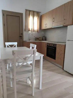 a kitchen with a white table and chairs and a refrigerator at Protopapas in Palaiochóra