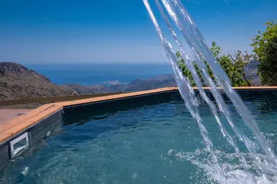 a water fountain in a pool with mountains in the background at Best View Mountain Villa in Teménia