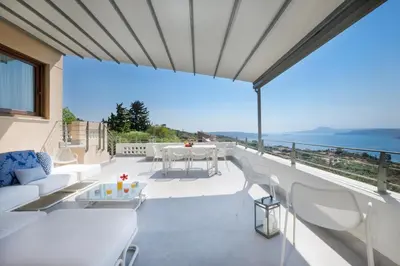 a balcony with white furniture and a view of the ocean at Kassiopeia Villa in Chania Town