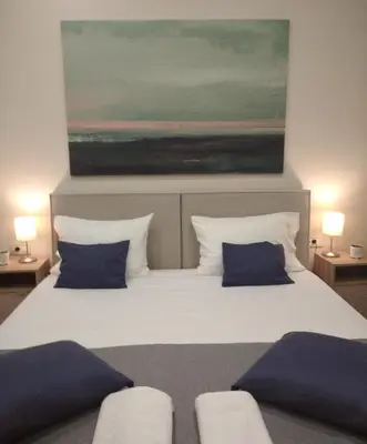 a large white bed with blue pillows and a painting at Marinos Suites in Chania Town