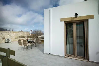 a patio with a table and chairs and a building at Agarathos Deluxe Homes In the Heart of Kaliviani Near Balos in Kissamos