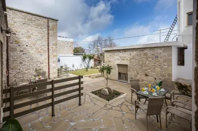 a patio with a table and chairs and a fireplace at Agarathos Deluxe Homes In the Heart of Kaliviani Near Balos in Kissamos
