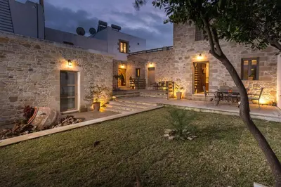 a stone house with a courtyard at night at Agarathos Deluxe Homes In the Heart of Kaliviani Near Balos in Kissamos