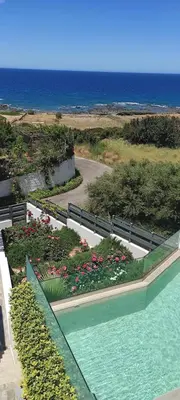 a swimming pool next to a garden with flowers at Sunset Elafonisi Apartments in Livadia