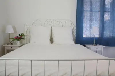 a bedroom with a white bed with blue curtains at Daphne's house Families Only in Chania Town