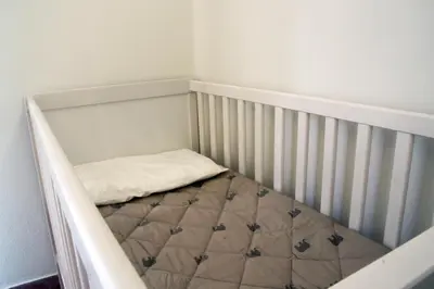a crib in a room with a bed in it at Daphne's house Families Only in Chania Town
