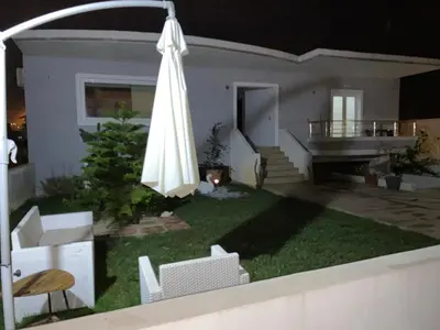 a yard with an umbrella and chairs and a house at Maria's modern studio 5min from beach in Souda