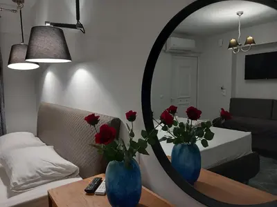 a living room with a mirror and two blue vases with red roses at GIANNIS in Galatás
