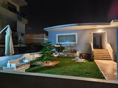 a house with a yard with a umbrella and a patio at Stellina's new studio 5min from beach in Souda