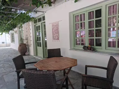 a patio with a wooden table and chairs and windows at Pension Irene in Sougia