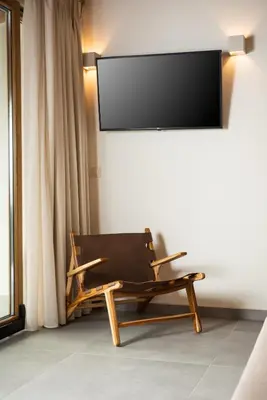 a chair in a room with a tv on a wall at Amaré Chania Luxury Residence in Stérnai
