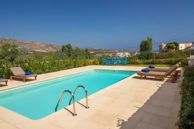 a swimming pool with two benches next to at Crete View in Marathi