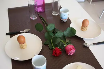 two eggs on plates on a table with roses at Crete View in Marathi