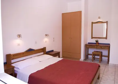 a bedroom with a bed and a dresser and a mirror at Anthea Apartments in Palaiochóra