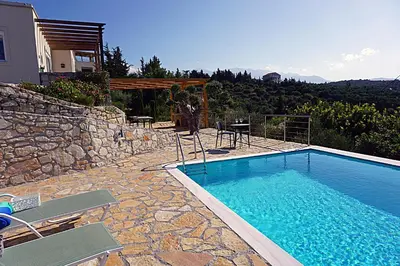 a swimming pool with chairs next to a house at Kukuwaia in Almirida