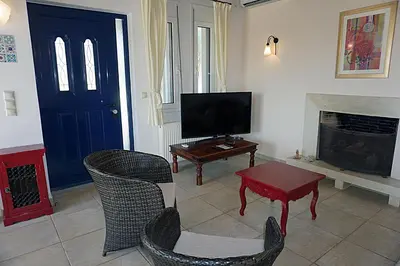 a living room with a television and a table and chairs at Kukuwaia in Almirida