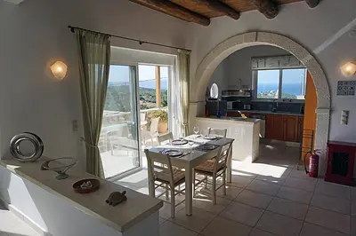 a living room with a table and a kitchen with a view at Kukuwaia in Almirida