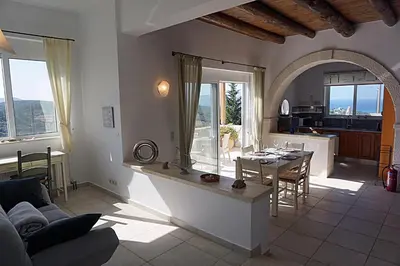 a living room with a table and a kitchen at Kukuwaia in Almirida