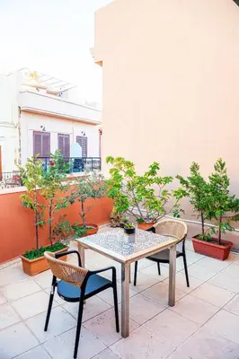 a table and chairs on a patio with trees at Alegria Pension in Chania Town