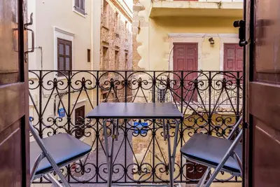 a table and two chairs on a balcony at Alegria Pension in Chania Town