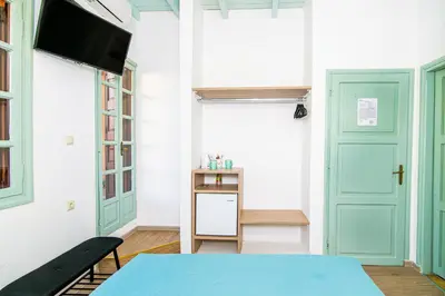 a room with green doors and a table and a tv at Alegria Pension in Chania Town